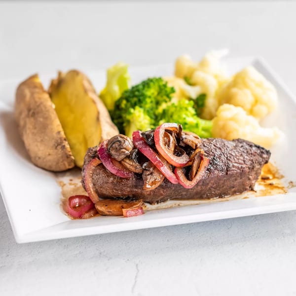 Grilled steak topped with sautéed red onions and mushrooms, served with a baked potato, broccoli, and cauliflower.