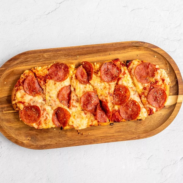 Pepperoni flatbread pizza, cut into slices, on a wooden serving board.