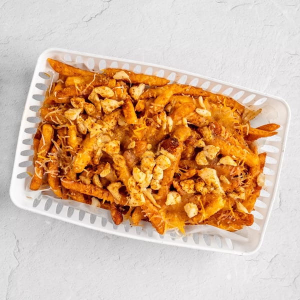 A white basket filled with golden-brown french fries, cheese curds, and shredded cheese.