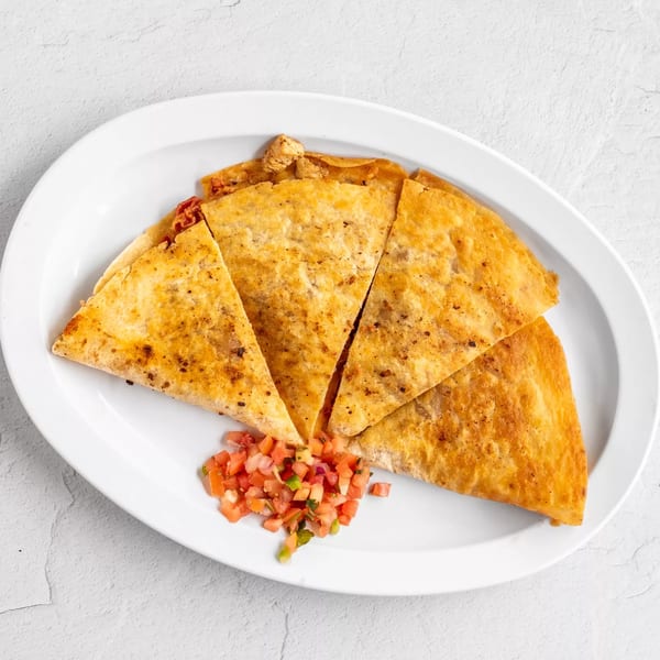 Golden-brown quesadilla wedges with chicken and pico de gallo on a white oval plate.