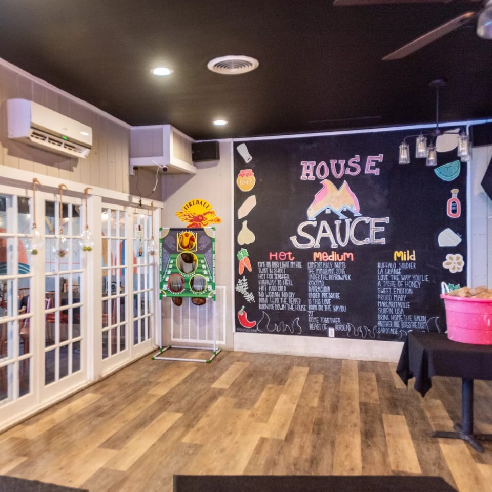 Interior of House Of Sauce with a large chalkboard menu, white French doors, and wooden floors.